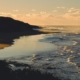 Two people walking along a quiet beach at sunset, a calm image of small daily activity