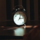 A classic alarm clock on a bedside table in soft light, representing the steady sleep and daily routine that support bipolar disorder stabilization