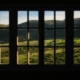 View of sunlit green hills through a multi-paned window from a quiet room