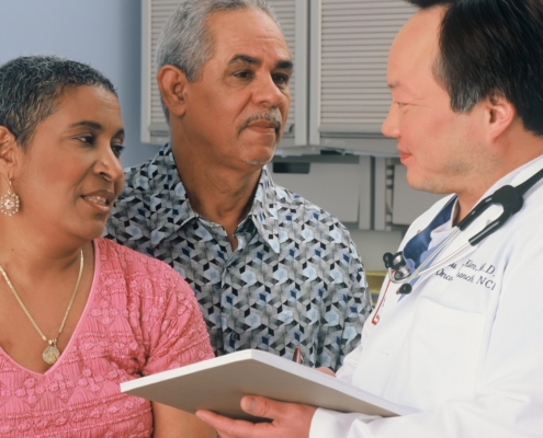 Clinician reviewing an aftercare plan on a tablet with a patient and family member during discharge planning