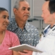 Clinician reviewing an aftercare plan on a tablet with a patient and family member during discharge planning