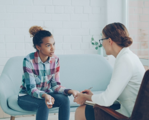 Therapist meeting with a young woman on a couch during a trauma-informed care session