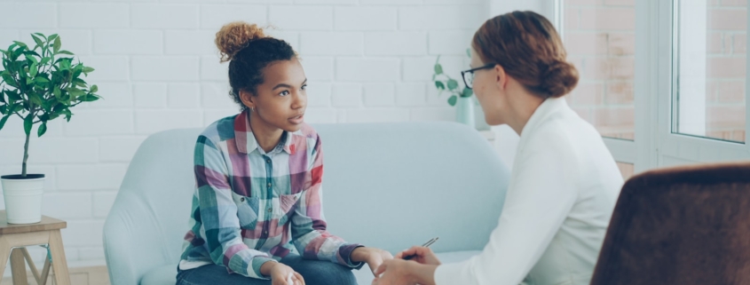 Therapist meeting with a young woman on a couch during a trauma-informed care session