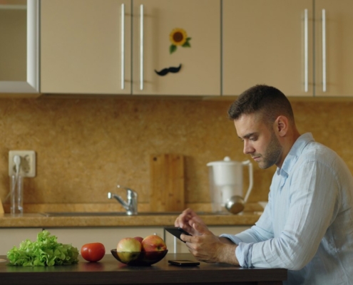 Man at a kitchen table looking up information on his phone