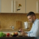 Man at a kitchen table looking up information on his phone