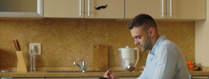 Man at a kitchen table looking up information on his phone