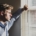 Person standing at a window in soft daylight, considering which level of mental health care to pursue