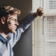 Person standing at a window in soft daylight, considering which level of mental health care to pursue