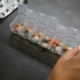 Hand taking a daily dose from a weekly pill organizer on a dark table, representing ongoing medical care alongside residential mental health treatment