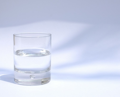 A clear glass of water on a white table in soft natural light