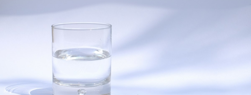 A clear glass of water on a white table in soft natural light