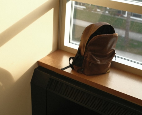 A packed backpack resting on a sunlit windowsill, ready for the trip home