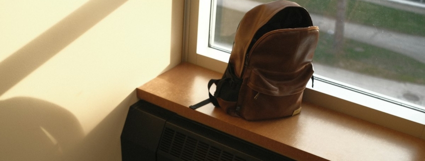A packed backpack resting on a sunlit windowsill, ready for the trip home