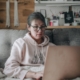 Woman sitting on a couch at home researching mental health treatment options on a laptop
