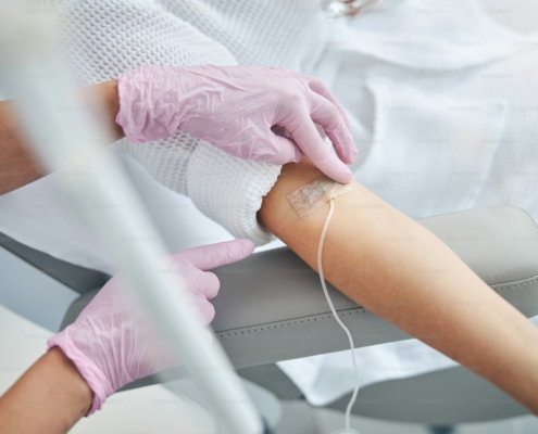 Nurse securing an IV catheter in a patient during a monitored ketamine infusion in a residential mental health setting