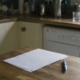 Sheets of paper and a pen on a wooden kitchen table, ready for writing down a medication history