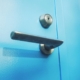 Close-up of a door lever and deadbolt lock on a bright blue door, representing checking compulsions addressed in exposure and response prevention for OCD