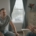 Two adults sitting and talking in a quiet, sunlit room, one listening while the other speaks