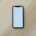 A plain black smartphone with a blank screen lying on a light wooden table