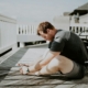 A man doing a seated forward stretch on a sunlit wooden porch, illustrating gentle physical activity during residential mental health treatment