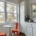 A sunlit kitchen with a small round table and two empty chairs beside a large window