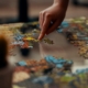 A hand placing a piece in a colorful jigsaw puzzle on a table, representing how psychological testing helps assemble a clearer clinical picture