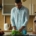 Woman on a phone call taking notes at a kitchen counter while her partner prepares a salad
