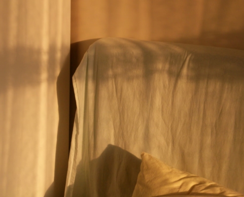 Warm morning light across bed linen representing restored sleep in residential care