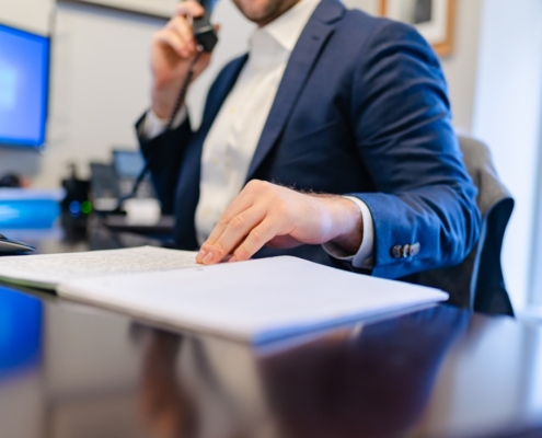 Person on the phone with plan documents in front of them, verifying insurance coverage for residential mental health treatment