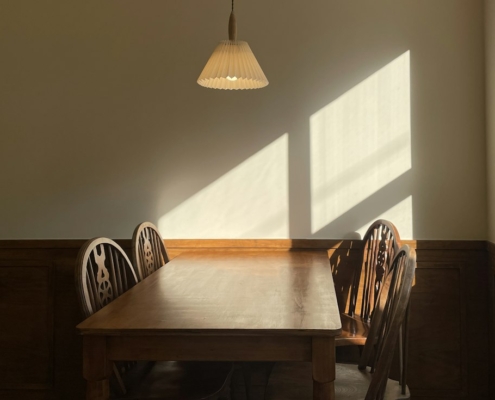 Warm afternoon light falling across a wooden table and chairs in a quiet room