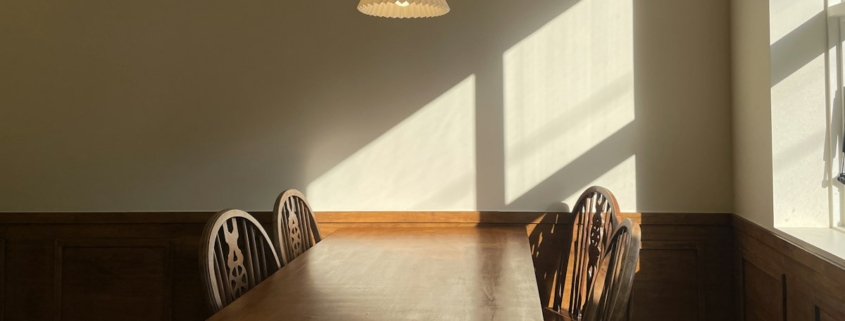 Warm afternoon light falling across a wooden table and chairs in a quiet room