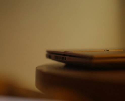 A closed laptop resting on a wooden table in soft warm light, representing stepping away from work for mental health treatment