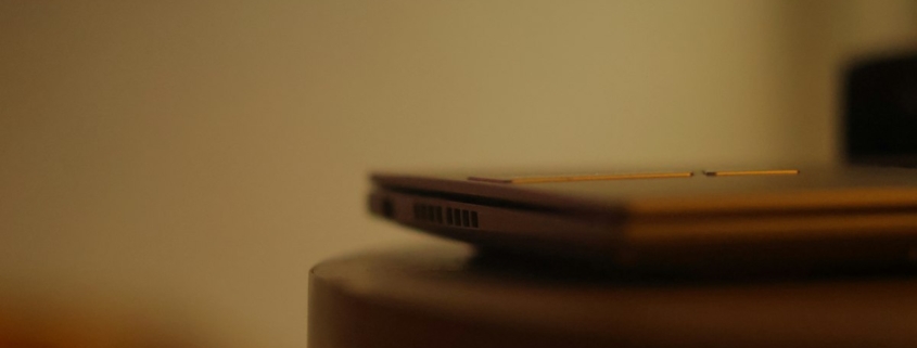 A closed laptop resting on a wooden table in soft warm light, representing stepping away from work for mental health treatment
