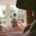 Person sitting quietly in a sunlit bay window, reflecting on whether to seek residential care